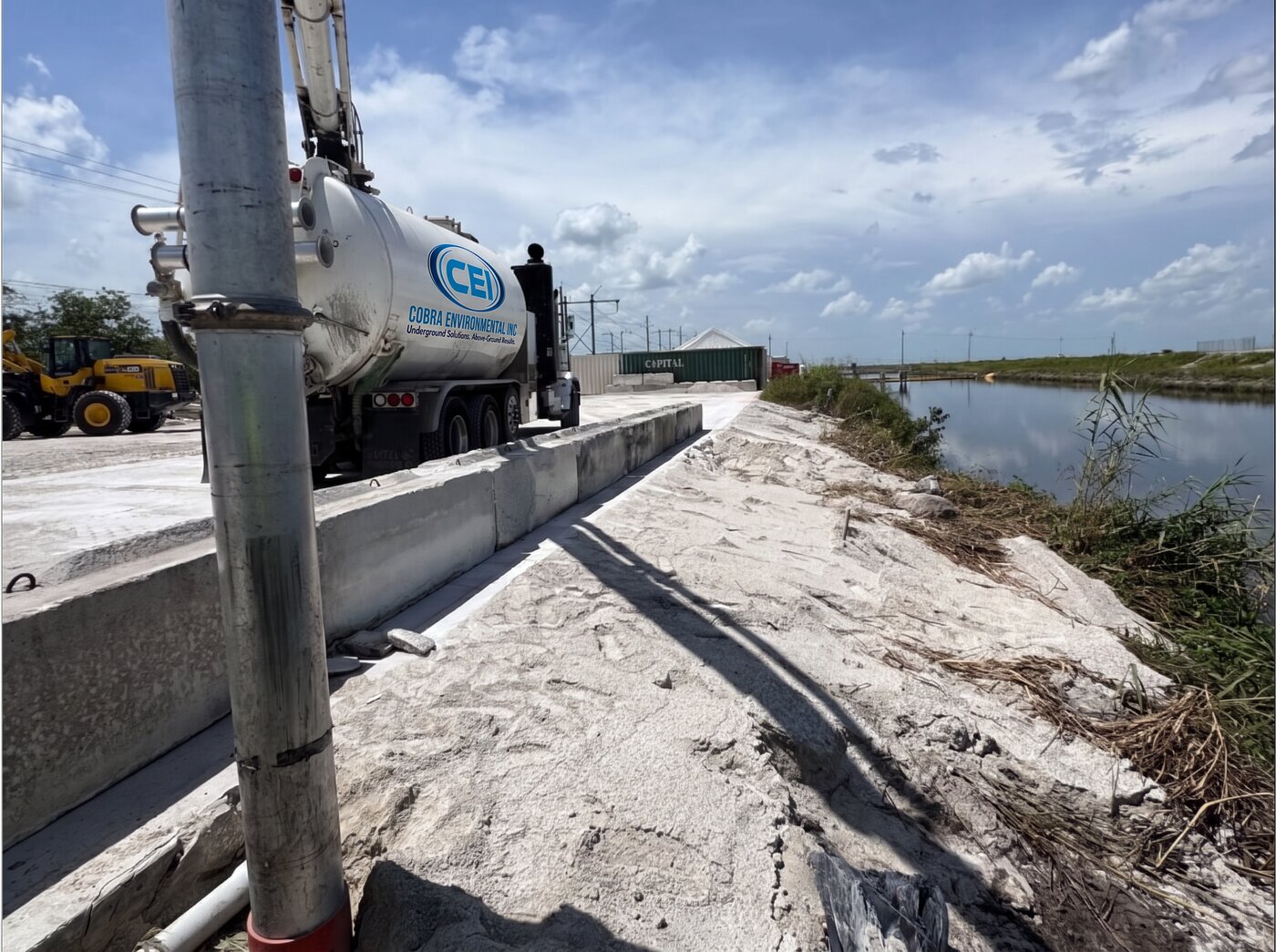 CEI vacuum truck staged on a narrow concrete berm alongside a canal — tight-access hydro excavation work